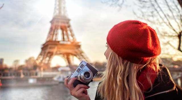Traveler holding a camera near a landmark